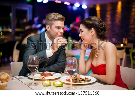 Affectionate couple in restaurant him feeding she Affectionate couple in restaurant him feeding she