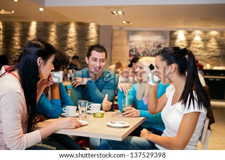 Five student friends communicating in cafe