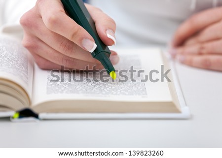 Highlighter  in female hand  marked text in book, education concept