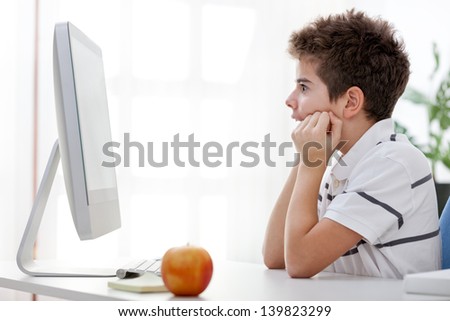 Very focused boy looking interesting move on computer screen