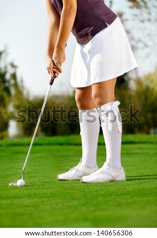 Female golfer swing golf ball on the grass