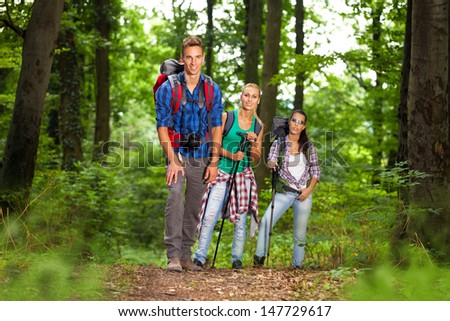 group of man and women during hiking excursion in woods, looking at camera and smiling
