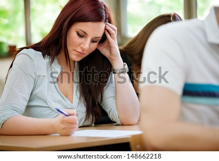 Young concentration student girl doing test in class