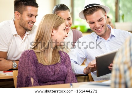 Group of happy students with tablet pc on break in classroom