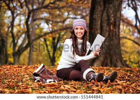 beautiful young  woman reading book in autumn park