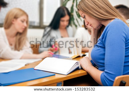 Students sitting at desk with books and learning