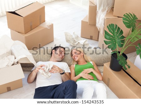 Young smiling couple relaxing in the middle of cardboard boxes Young smiling couple relaxing in the middle of cardboard boxes