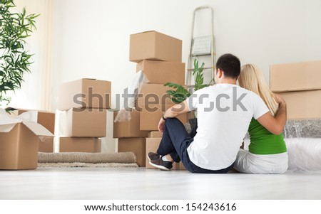 Couple sitting  and looking  lot of moving boxes, back view