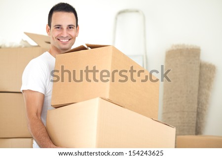 Smiling handsome man carrying packages during moving house