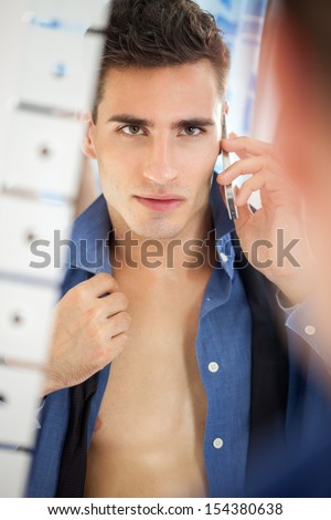 Sexy young men preparing for job looking at himself in mirror