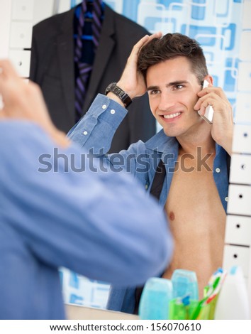 Young man an looks himself at mirror while preparing for job