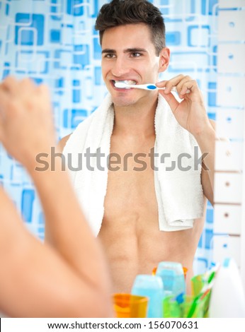 Young handsome man brushing teeth front of mirror