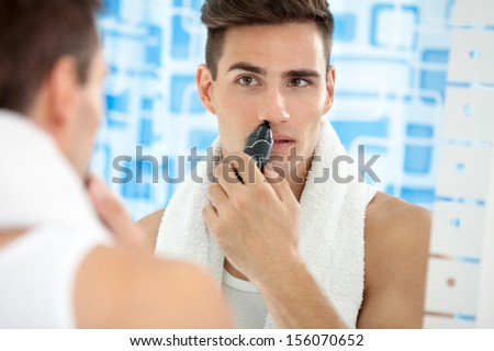 handsome young man remove hair from his nose with trimmer