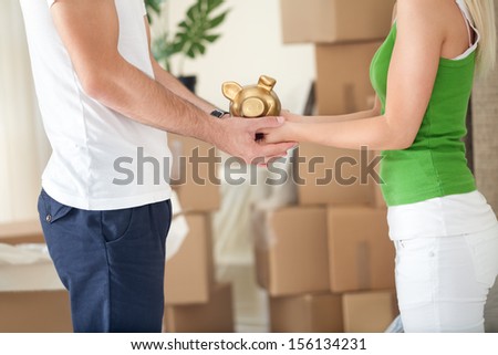 Couple holding piggy bank in their new home