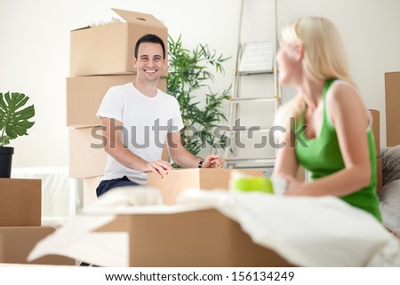 excited couple in new home unpacking boxes, concept moving into a new home.
