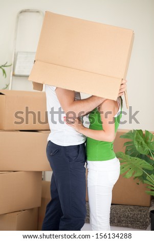 Happy young couple staying together in their new common flat and kissing under the box