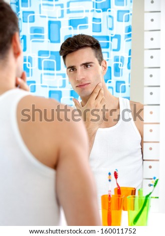 young man looks in the mirror in the bathroom