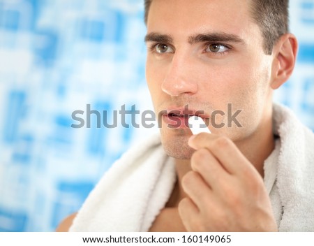 Handsome  man  applying balsam for lips, care of  lips