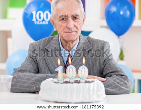 Senior men sitting front of cake for 100th birthday