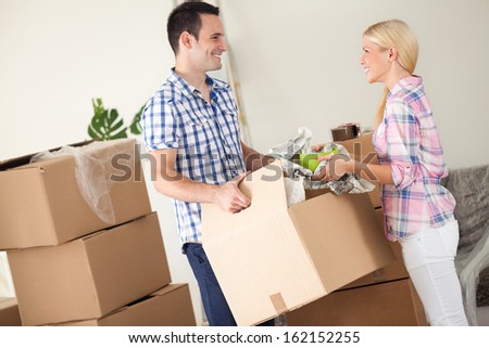 Couple with box moving into new home,  smiling