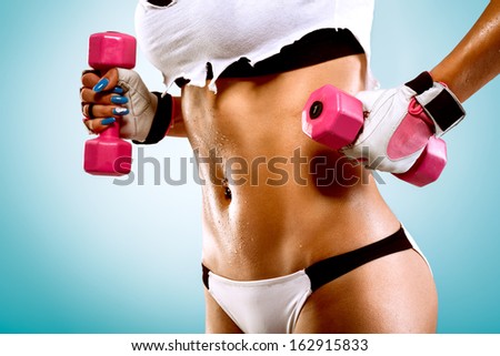 Body of a young fit woman lifting dumbbells