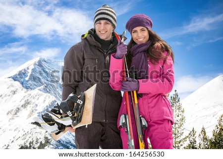 Portrait of a man and a woman smiling with skis in snow