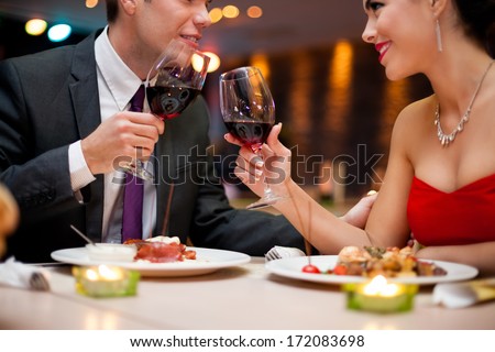 hands of couple toasting their wine glasses over a restaurant table during a romantic dinner hands of couple toasting their wine glasses over a restaurant table during a romantic dinner