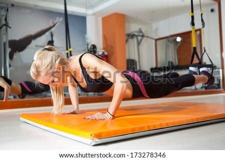 Young Woman Doing Push-Ups While Legs Hanging On Elastic Rope