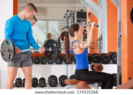 young man and woman doing weight training at gym
