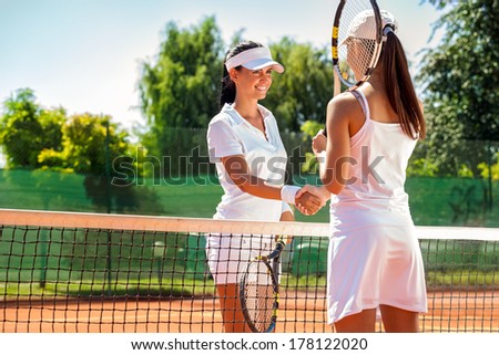 Women handshaking after playing a tennis match
