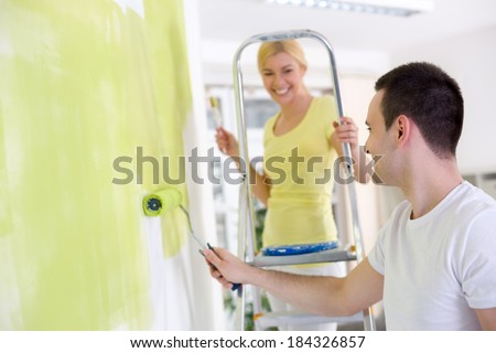 Cheerful couple  painting wall in their new house