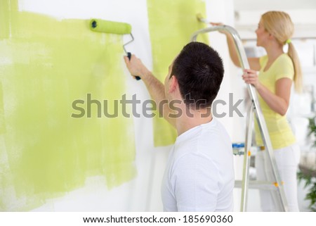 Couple in their new home painting wall in green