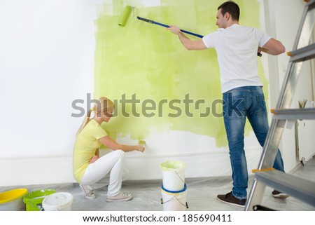 Young couple painting wall in their room