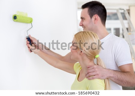 Affectionate  young couple painting wall together