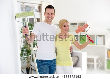 Smiling couple with paint roller,  renovation or decorated home