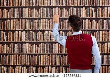 Young man in library take book from shelf