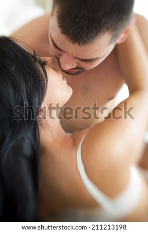 Sexy young couple kissing and playing in bed- shoot with lensbaby