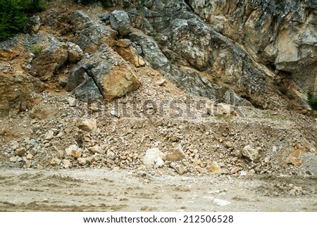 road is blocked by a land slide of rock and debris to where it is a hazard for drivers in cars