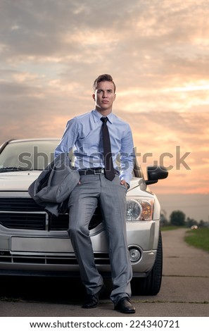 Handsome young man leaning on his car. Attractive gorgeous guy standing, outdoors - outside
