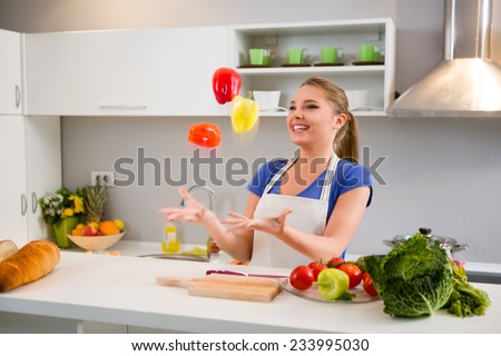 Young woman  juggle with vegetables in kitchen