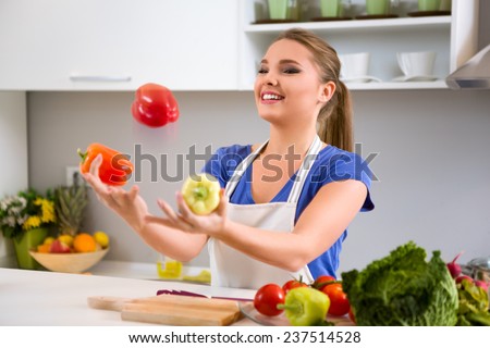 Young woman having fun in kitchen, juggle with vegetables
