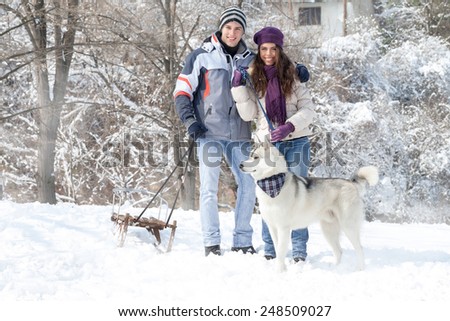 Happy young couple walking with dog snowy forest