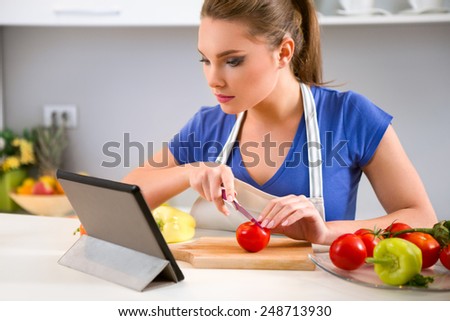 young woman preparing food and looking at tablet, looking for a recipe on the internet