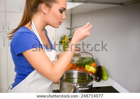 young woman cooking and testing the food in the kitchen