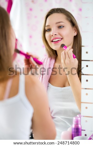 Young girl applying powder on her face with brush for powder