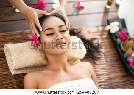 Portrait of young beautiful Balinese woman receiving head massage at spa