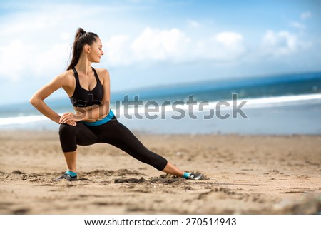 Attractive fit woman stretching  on beach, outdoor workout