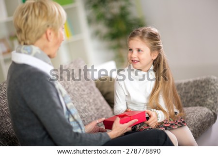 Cute girl giving her grandmother a gift, concept grandmother day
