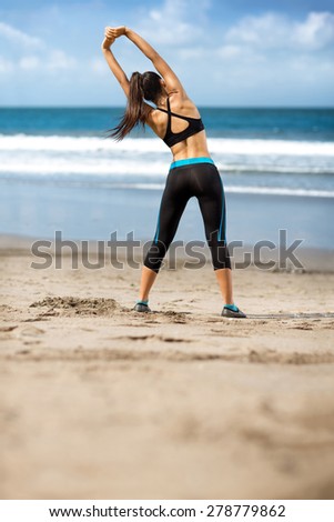 Female stretching arms and breathing exercises in morning at beach