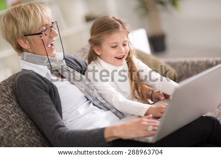 Happy little girl and  granny together using laptop at home